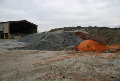 Skládka vstupních surovin – v pozadí odležená hlína, v popředí příměsi – vlevo odpadní buničina z výroby papíru, vpravo cihelný prach z broušení cihel.